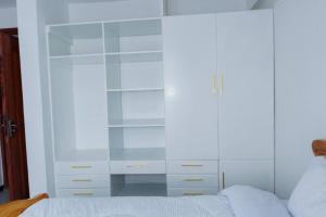 a bedroom with a white cabinet next to a bed at Pearl Homes Nanyuki in Nanyuki