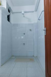 a white bathroom with a shower and a tile floor at Pearl Homes Nanyuki in Nanyuki