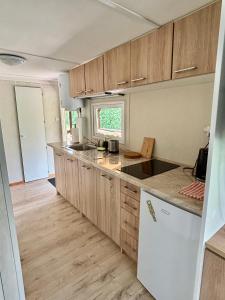 a kitchen with wooden cabinets and a white refrigerator at Domek z widokiem na las in Nielisz