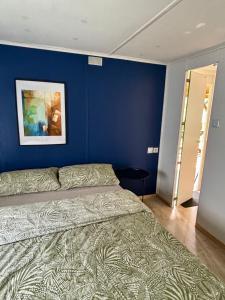 a bedroom with a bed with a blue wall at Domek z widokiem na las in Nielisz +11 photos