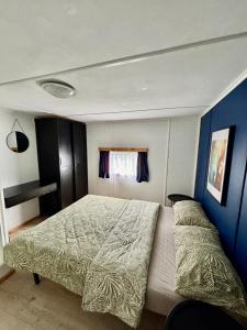 a bedroom with a large bed and a blue wall at Domek z widokiem na las in Nielisz