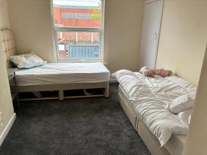 two beds in a room with a window at Cute Central House Sleeps 4 in Stafford
