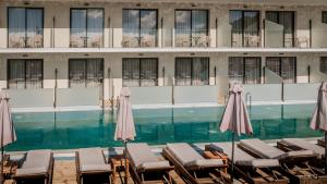 a swimming pool with chairs and umbrellas in front of a building at La Mirage Hotel in Tsilivi