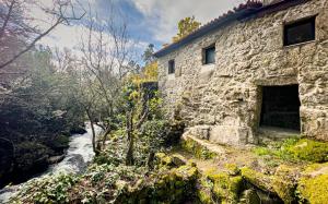 an old stone building next to a river at Wylde Roots River House - with natural river swimming pools in Couto de Baixo