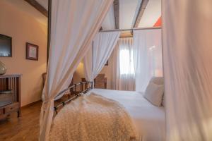 a bedroom with a bed with curtains and a window at Casona De Torres in Mondéjar