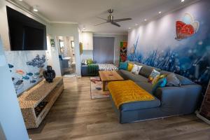 a living room with a blue couch and a flat screen tv at The Butterfly Villa in Pringle Bay