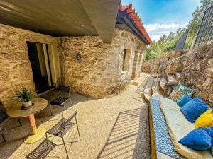 a porch with a bed and a table and chairs at Wylde Roots River House - with natural river swimming pools in Couto de Baixo +13 photos