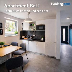 a kitchen with white cabinets and a table and chairs at Apartment_BaLi in Linkenheim-Hochstetten