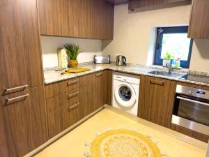 a kitchen with wooden cabinets and a washer and dryer at Wylde Roots River House - with natural river swimming pools in Couto de Baixo
