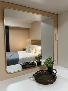 a mirror reflecting a bedroom with a bed and two plants at Lovista in Tygerberg Hills