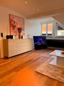 a living room with a flat screen tv and a wooden floor at Design Dachgeschoss Wohnung in Eilenburg