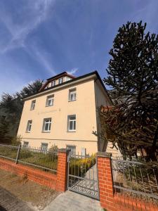 a white house with a fence in front of it at Design Dachgeschoss Wohnung in Eilenburg