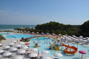 a large swimming pool with a water park with umbrellas at Villa Greif Apartment in Lignano Sabbiadoro
