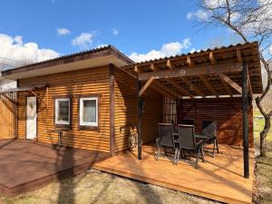 a wooden cabin with a table and chairs on a deck at Katase Tiny House, Secluded Beachfront Cabin on Lake Peipus in Katase