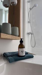 a bathroom with a shower and a bottle of spa on a towel at Lola des Sources in Spa +9 photos