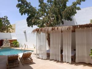 a patio with a pool and chairs and a house at Maison Talouma in Saly Portudal