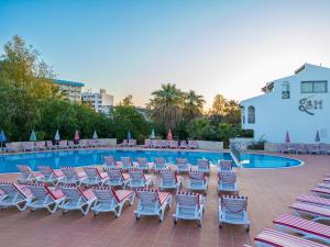a group of lounge chairs and a swimming pool at Sentinus Beach Hotel in Kuşadası