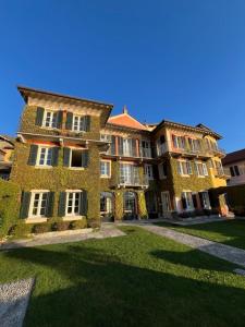 a large brick building with grass in front of it at Relais Villa Margherita in Oggebbio