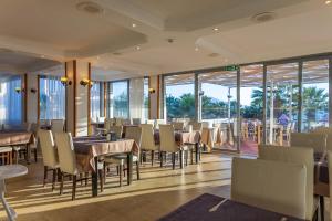 a restaurant with tables and chairs and windows at Sentinus Beach Hotel in Kuşadası