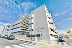 a white building with cars parked in a parking lot at Domocenter Apartamentos Turísticos in Bormujos