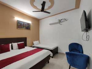 a bedroom with a bed and a chair and a tv at Hotel Basant in Amritsar