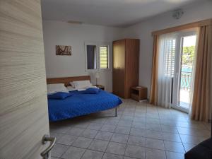 a bedroom with a blue bed and a window at Apartments Dora, with a beautiful view of the bay, near the sea and center in Vrboska