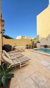 a patio with lounge chairs and a swimming pool at L'Artiste Guest House in Xagħra