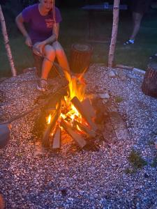 a woman sitting next to a fire at Slow life Karkonosze in Wojcieszyce
