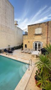 a swimming pool in front of a brick building at L'Artiste Guest House in Xagħra