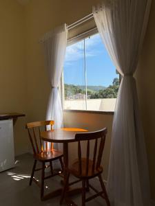 a table and two chairs in a room with a window at Suíte confortável no centro da cidade in Miguel Pereira