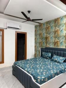 a bedroom with a blue bed with a painting on the wall at Aanya Bnb in Zirakpur