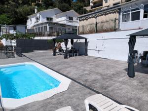 a swimming pool with umbrellas and chairs next to a house at Espacio Kybalion in Argentona