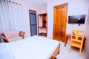 a bedroom with a bed and a chair and a desk at Clisa Rest House in Karatu