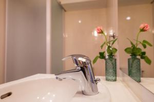 a bathroom sink with a faucet and two vases with flowers at Le clos aux roses in Chédigny +67 photos