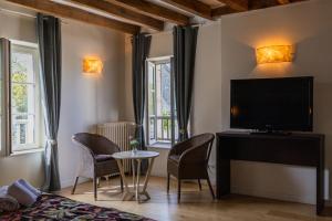 a room with a tv and chairs and a table at Le clos aux roses in Chédigny