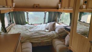 a small room with a bed in the back of a van at Fern Meadow Caravan 1 in Saint-Michel-de-Montjoie