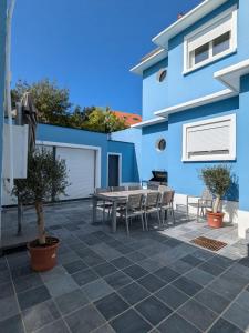 a patio with a table and chairs in front of a blue building at Villa Gisèle in Le Touquet-Paris-Plage