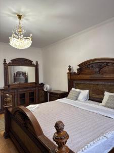 a bedroom with a large wooden bed and a chandelier at spacious apartment in Almaty