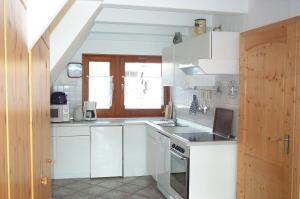 a white kitchen with a sink and a stove at PRHS08001-FeHaus-Diekkroon in Presen