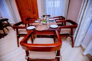a dining room table with chairs and plates at Clisa Rest House in Karatu