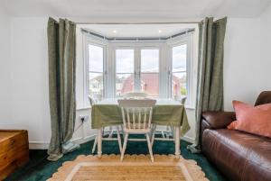 a dining room with a table and a couch at New Forest Flat Steps from Brockenhurst Station, Sleeps 4 in Brockenhurst