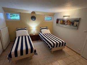 two beds in a room with two windows at Les Acacias in La Milesse