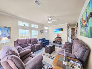a living room with leather couches and a table at It's a Shellabration home in Crystal Beach
