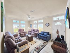 a living room with couches and chairs and a clock at It's a Shellabration home in Crystal Beach