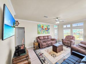 a living room with leather furniture and a flat screen tv at It's a Shellabration home in Crystal Beach