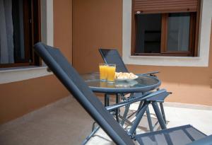 a table with two glasses of orange juice and two chairs at Agnanti in Agia Fotini