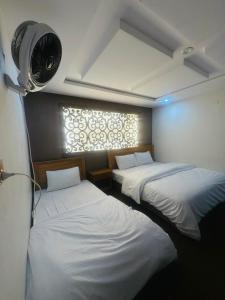 two beds in a room with a fan and a window at North Paradise Guest House in Skardu