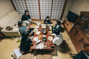 a group of people sitting around a table eating at 民泊やまねこ in Yachi