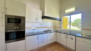 a large kitchen with white cabinets and a window at Golfe - Shared Pool - 7 Pax - Vilamoura in Vilamoura