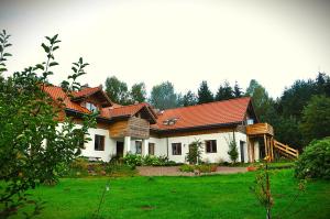 a house with a red roof on a green field at Forreset esencja natury - apartament z opcją sauny i balii in Gietrzwałd